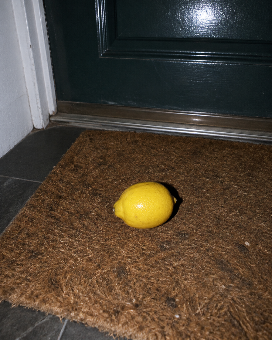 A lemon lying on a doormat at night